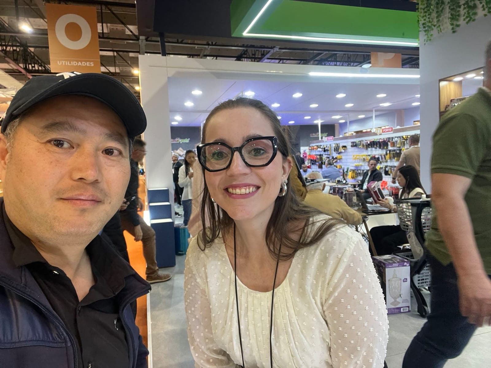 Izabela com fornecedor em corredor de feira de utilidades e ferramentas